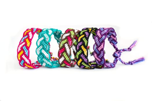 Multicolored woven DIY friendship bracelets handmade of embroidery bright thread with knots isolated on white background