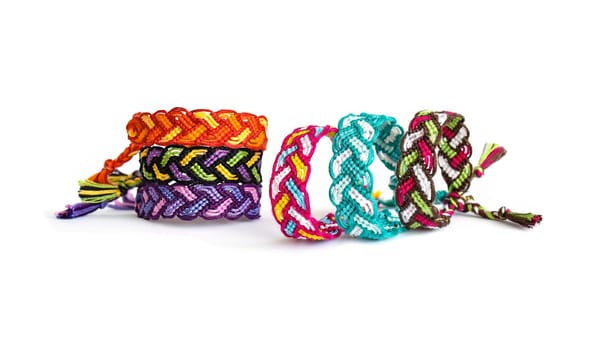Multicolored woven DIY friendship bracelets handmade of embroidery bright thread with knots isolated on white background