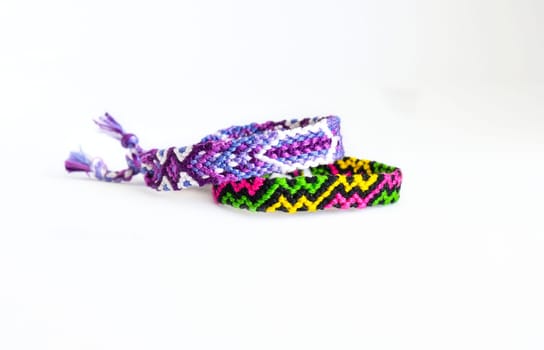 Multicolored woven DIY friendship bracelets handmade of embroidery bright thread with knots isolated on white background