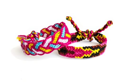 Multicolored woven DIY friendship bracelets handmade of embroidery bright thread with knots isolated on white background