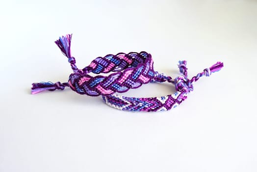 Multicolored woven DIY friendship bracelets handmade of embroidery bright thread with knots isolated on white background