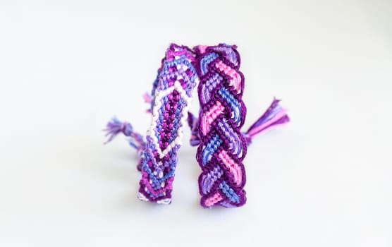 Multicolored woven DIY friendship bracelets handmade of embroidery bright thread with knots isolated on white background
