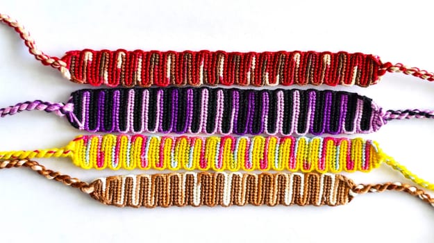 Multicolored woven DIY friendship bracelets handmade of embroidery bright thread with knots isolated on white background
