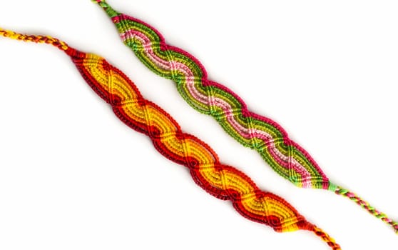 Multicolored woven DIY friendship bracelets handmade of embroidery bright thread with knots isolated on white background