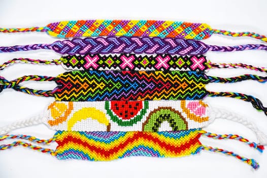 Multicolored woven DIY friendship bracelets handmade of embroidery bright thread with knots isolated on white background