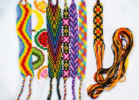 Multicolored woven DIY friendship bracelets handmade of embroidery bright thread with knots isolated on white background
