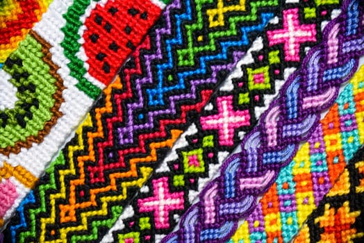 Multicolored woven DIY friendship bracelets handmade of embroidery bright thread with knots isolated on white background