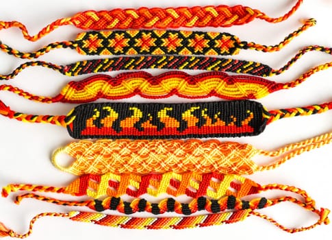 Woven DIY friendship bracelets handmade of embroidery floss with knots. Fire colors