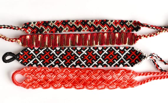 Woven DIY friendship bracelets handmade of embroidery red thread with knots on white background