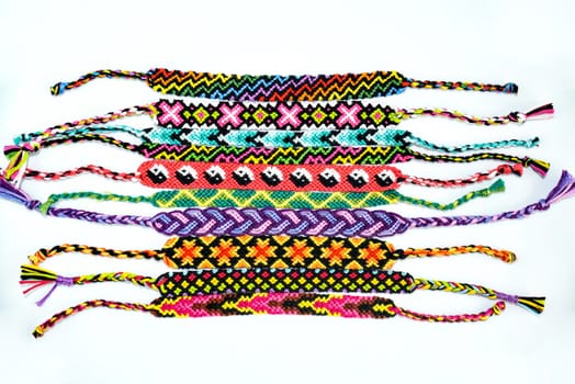 Multicolored woven DIY friendship bracelets handmade of embroidery bright thread with knots isolated on white background