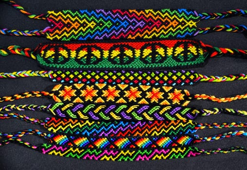 Woven DIY friendship bracelets handmade of embroidery bright thread with knots on black background.