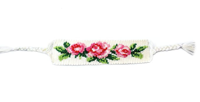 Woven DIY friendship bracelet with bright flower pattern Rose handmade of thread isolated on white background