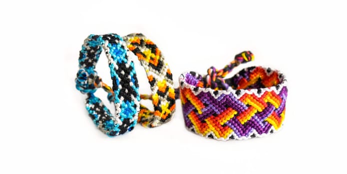 Multicolored woven DIY friendship bracelets handmade of embroidery bright thread with knots isolated on white background