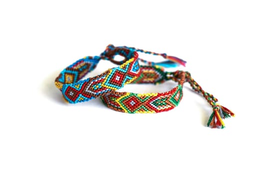 Multicolored woven DIY friendship bracelets handmade of embroidery bright thread with knots isolated on white background