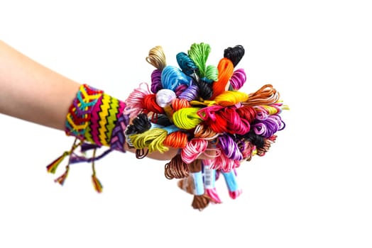 Many embroidery thread for friendship bracelets in hand. Female hand with handmade bracelets on wrists. White background with copy space
