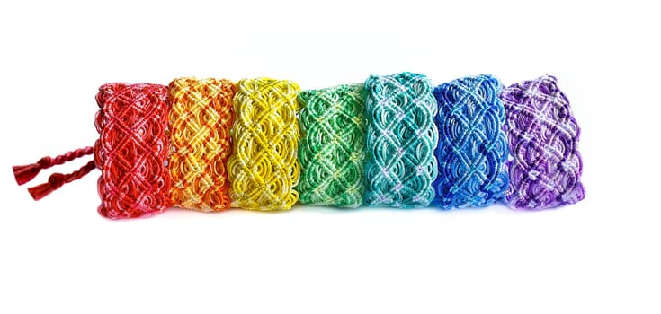 Multicolored woven DIY friendship bracelets handmade of embroidery bright thread with knots isolated on white background