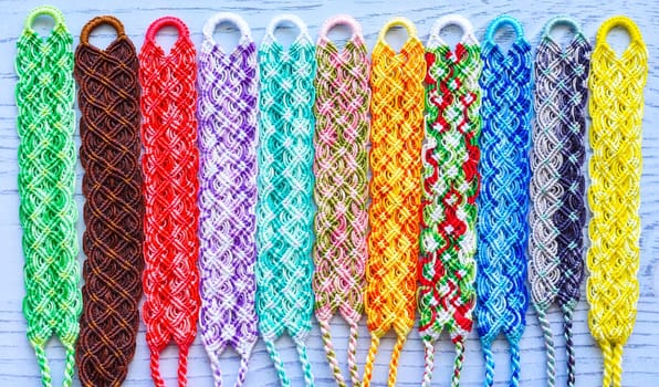 Multicolored woven DIY friendship bracelets handmade of embroidery bright thread with knots isolated on white background