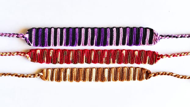 Multicolored woven DIY friendship bracelets handmade of embroidery bright thread with knots isolated on white background
