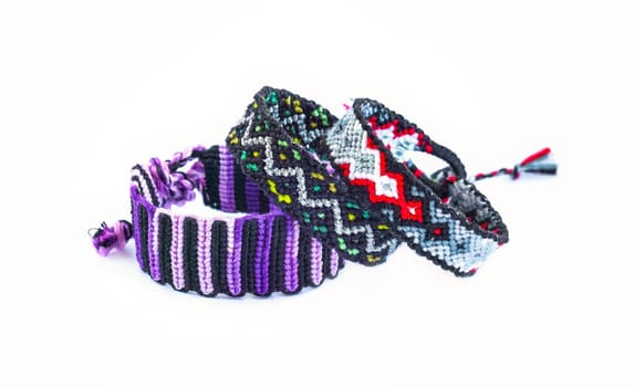 Multicolored woven DIY friendship bracelets handmade of embroidery bright thread with knots isolated on white background