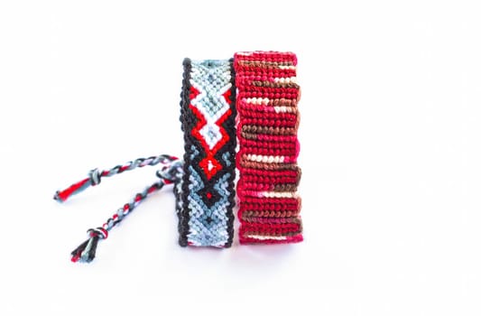 Multicolored woven DIY friendship bracelets handmade of embroidery bright thread with knots isolated on white background