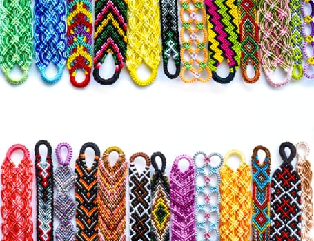 Woven DIY friendship bracelets handmade of embroidery bright thread with knots on white background.