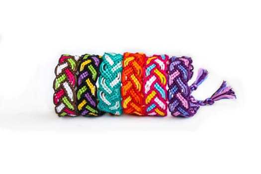 Multicolored woven DIY friendship bracelets handmade of embroidery bright thread with knots isolated on white background