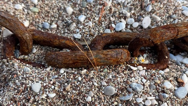 A large rusty chain on a pebble beach, washed up by a wave during a storm. High quality photos