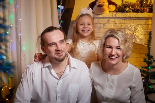 A cheerful family gathers indoors to celebrate Christmas, surrounded by decorations and a glowing Christmas tree.