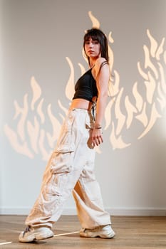 A skilled dancer displays fluid movements in a spacious studio, wearing casual attire. The backdrop features artistic flame designs, enhancing the energetic atmosphere.