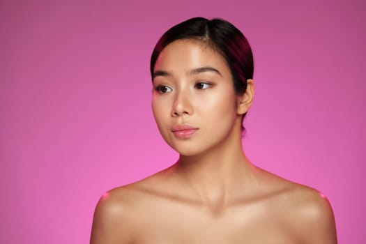A model with smooth skin poses gracefully in soft lighting, wearing no clothing. The vibrant pink background highlights her features and enhances the overall aesthetic.