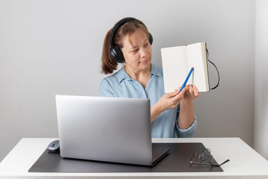 Cheerful freelance professional woman wearing big headphones talking on online chat meeting using laptop, speaking on video conference call, smiling, enjoying work online communication