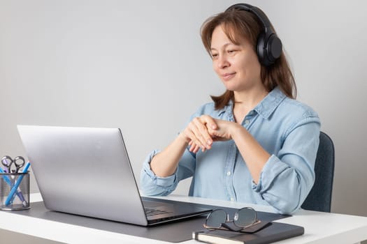 Cheerful freelance professional woman wearing big headphones talking on online chat meeting using laptop, speaking on video conference call, smiling, enjoying work online communication