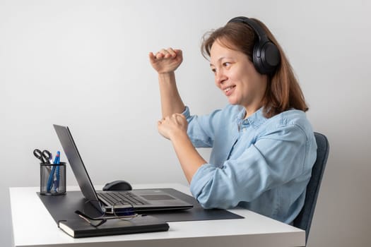 Cheerful freelance professional woman wearing big headphones talking on online chat meeting using laptop, speaking on video conference call, smiling, enjoying work online communication