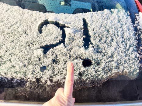 Frost covers a car window with a question mark, suggesting uncertainty about how to deal with the snowy weather conditions.