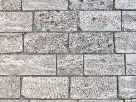 This textured stone background features gray bricks arranged in a structured pattern, providing a clean, minimalistic space for text or designs.