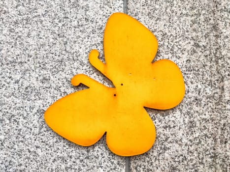 A vibrant yellow butterfly adorns a gray textured surface, creating an eye-catching display with ample copy space for creative use.