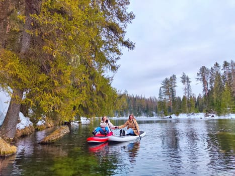 Kirov, Russia - March 14, 2024: A couple paddleboards together on a calm lake, surrounded by winter trees and a peaceful landscape under a cloudy sky.