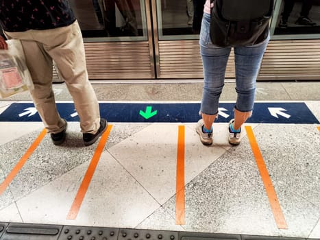 Hong Kong, China - April 09, 2024 - Commuters patiently stand at a subway platform in Hong Kong, waiting for the next train during busy hours.