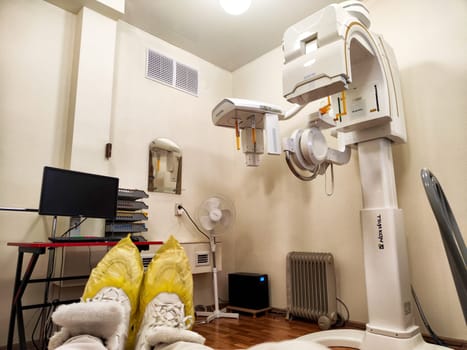 Kirov, Russia - November 28, 2024: Patient preparing for an X-ray examination in a hospital room equipped with advanced imaging technology and supportive equipment.