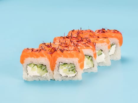 Studio photography of Philadelphia Roll of velvety cream cheese and cucumber wrapped in perfect seasoned sushi rice and fresh salmon, decorated microgreens. Isolated on solid light blue background