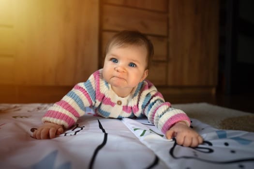 Grumpy cute baby girl lying on baby mat. Adorable kid portrait. 6 month old child. Childhood concept. High quality photo