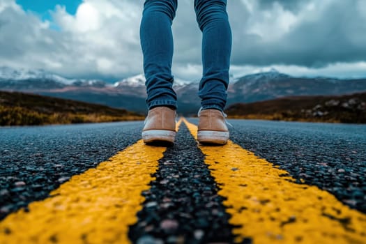 A person is standing on a road with yellow lines. The road is empty and the sky is cloudy