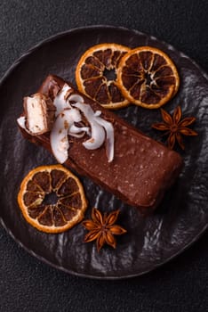Piece of sweet chocolate bounty cake with coconut flakes and sponge cake on dark concrete background