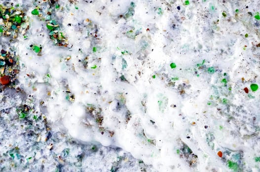 Background ice with multi-colored glass. Glass beach, Japanese sea, Russia.