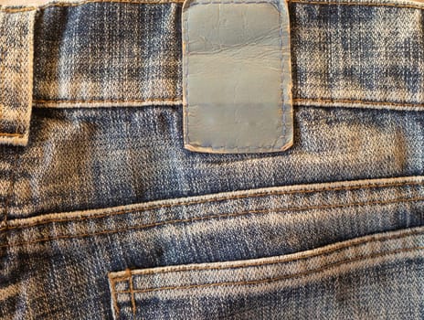 Denim background with stitching and empty label with copy space for graphic design. Blank label for branding and care messages.