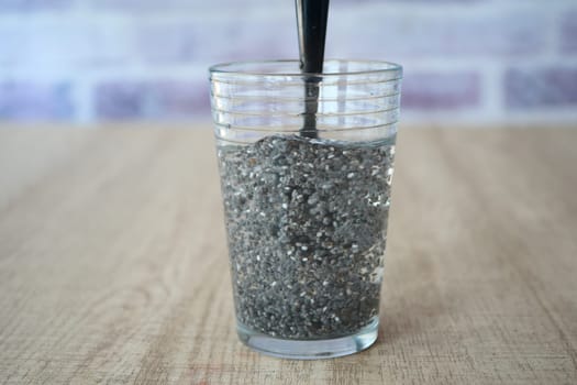 Chia seeds are absorbing water in a glass cup.