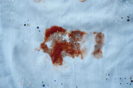 Red sauce dribbles on a white cloth after dining.