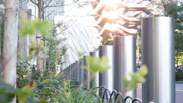 New York City, United States - 1 Sept 2023: Hudson Yards Vessel, urban architecture in Chelsea, Manhattan Midtown, NYC, USA. Street perspective, famous tourist landmark. Park greenery, sun reflection.
