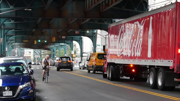New York City, United States - 13 Sept 2023: Coca-cola truck, elevated subway above street. Metropolitan bridge over road, Queens. Long Island metro line. Coca cola delivery, Coke lorry, railway track