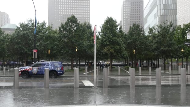New York City, United States - 10 Sept 2023: Manhattan Downtown Financial District. People with umbrella on rainy day. World Trade Center Oculus, memorial 911 Museum, Police car on Greenwich street.